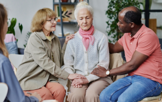 People comforting elder woman.