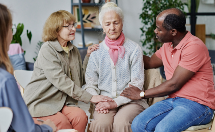 People comforting elder woman.