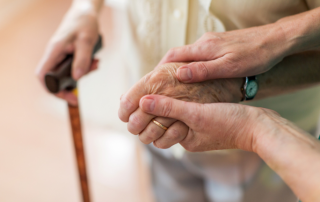 Elder holding hands with caregiver