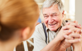 Old man smiling holding hands with caregiver