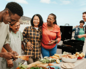 Blended family smiling while barbecuing and prepping a lovely meal.