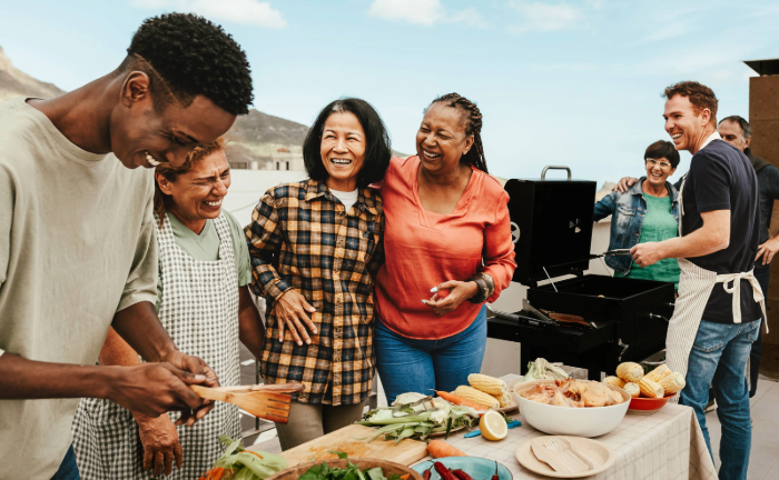 Blended family smiling while barbecuing and prepping a lovely meal.