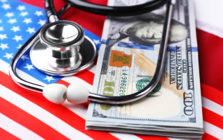 Stethoscope and a stack of money sitting on top of the American flag.